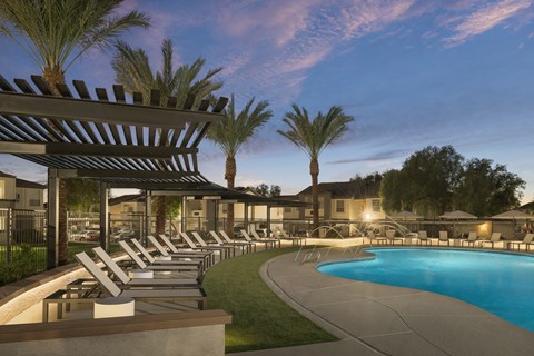 a swimming pool with chaise lounge chairs at night