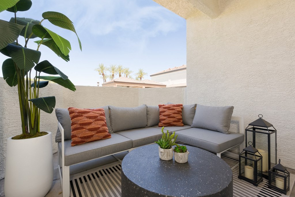 a patio with couches and a table with potted plants