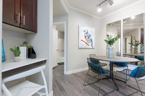 a dining room area with a table and chairs and a window