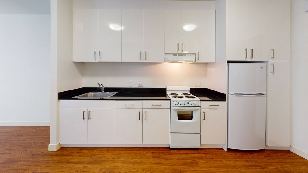 a kitchen with white cabinets and black countertops