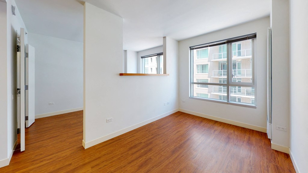 a bedroom with a large window and hardwood floors