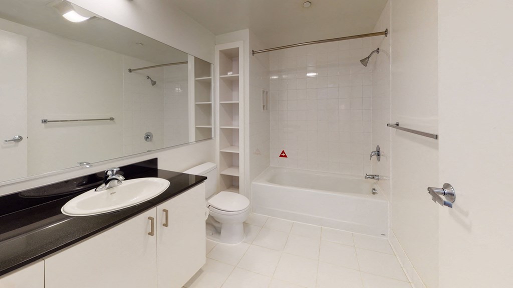 a bathroom with a white bathtub and a white sink with a black countertop