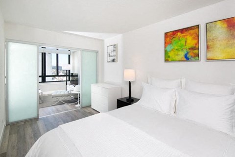 a bedroom with a white bed and two paintings on the wall