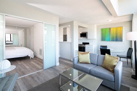 A modern living room with a grey couch and a glass table.