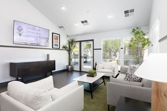 a living room with white couches and chairs and a tv on the wall