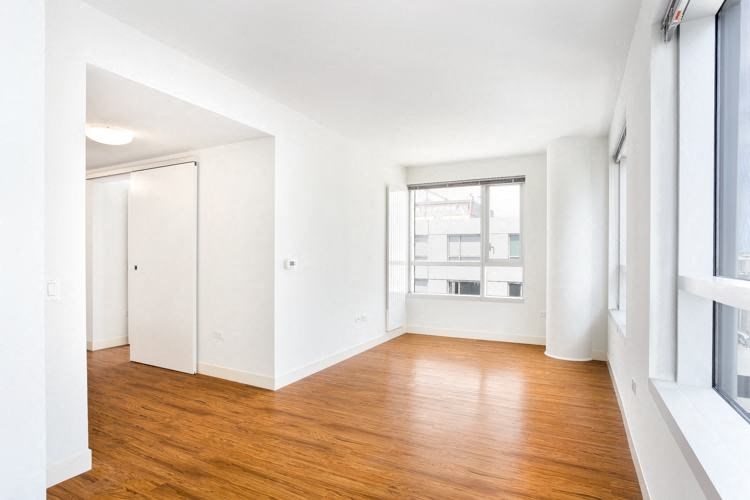 a bedroom with hardwood floors and a large window