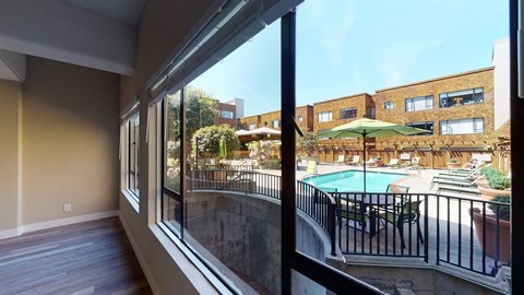 a large window looking out onto a pool and patio with umbrellas
