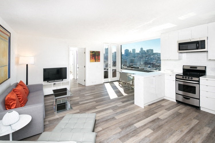 an open living room and kitchen with a large window and a view of the city