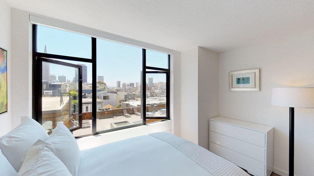 a bedroom with a large window and a white bed
