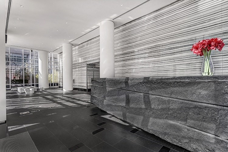 a vase of red flowers sits on top of a large stone desk in a large lobby