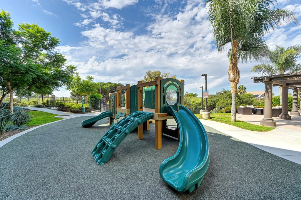 A playground with a green slide and a wooden structure.