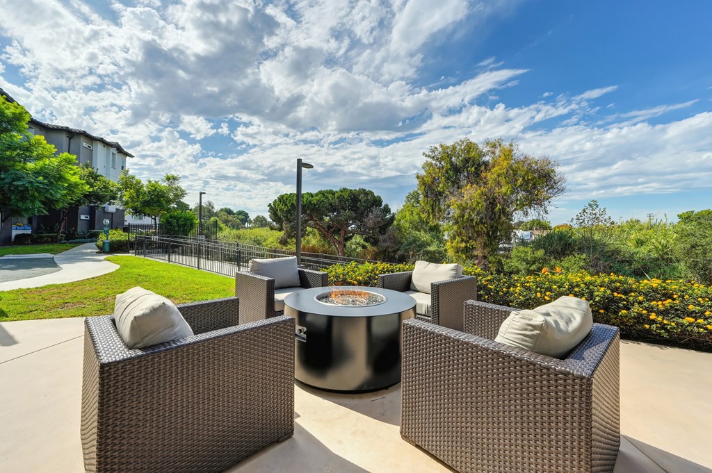A fire pit and chairs overlooking a green lawn.