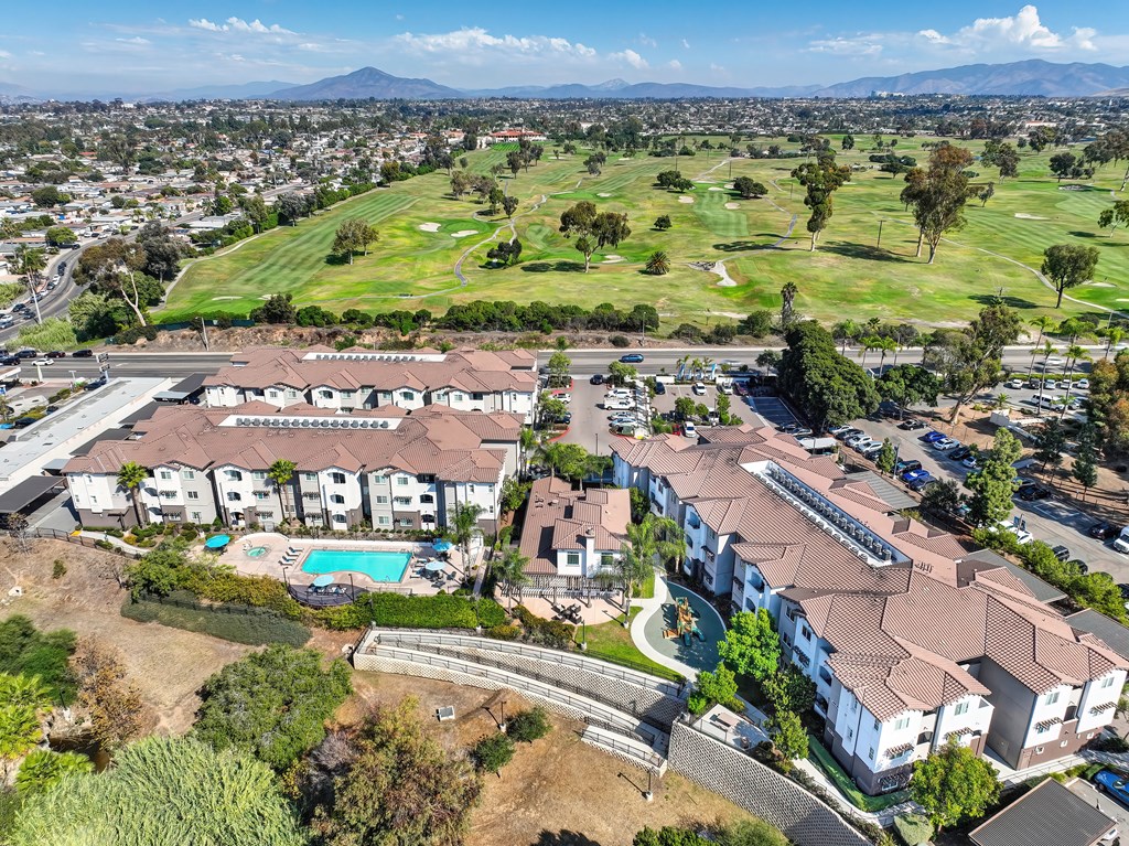 A large apartment complex with a pool and a golf course in the background.