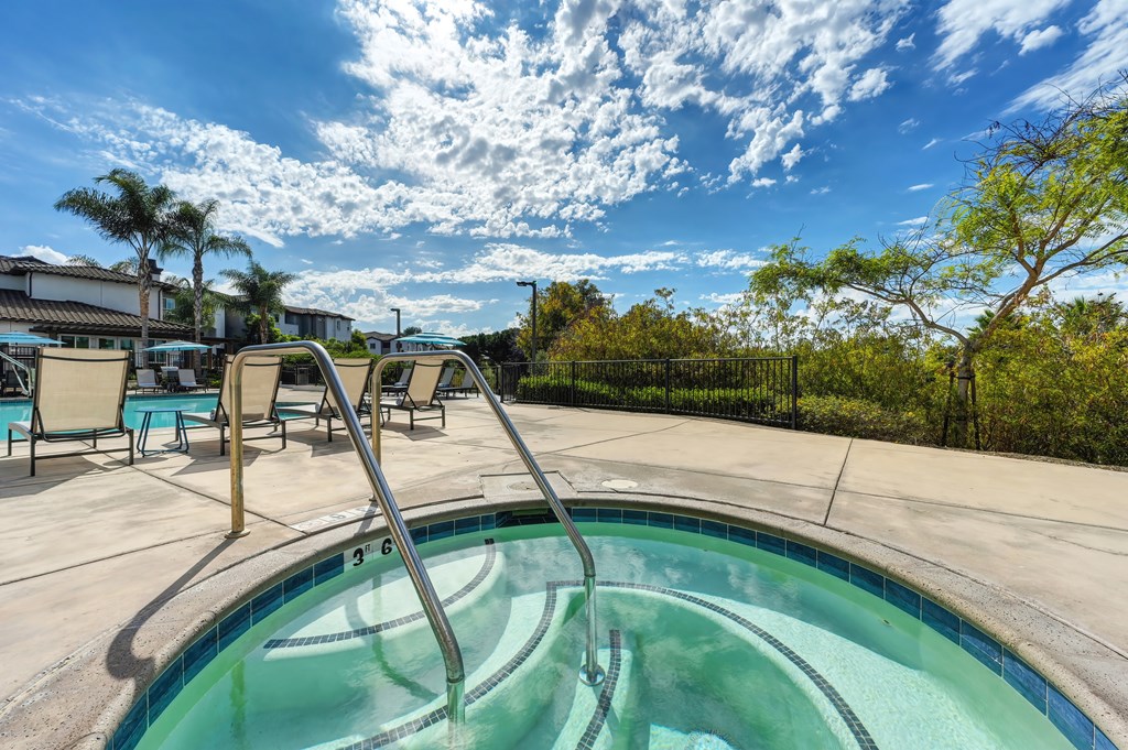 A hot tub sits in the middle of a patio surrounded by chairs.