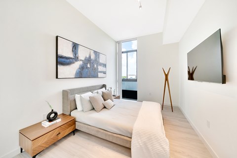 A bedroom with a bed, a wooden table, and a painting on the wall.