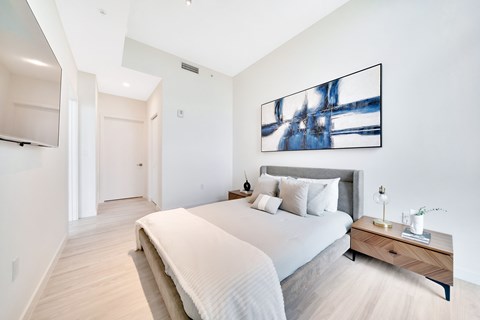 A bedroom with a large bed and a painting on the wall.