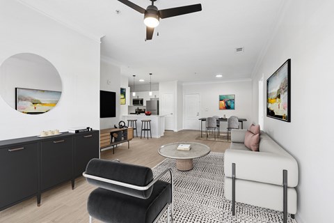 A living room with a black and white patterned rug, a black chair, a white sofa, and a painting on the wall.