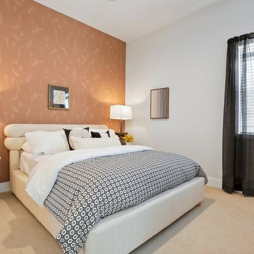 A bed with a white headboard and a black and white patterned comforter.