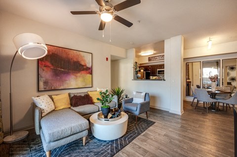 A living room with a grey couch, a white coffee table, and a painting on the wall.