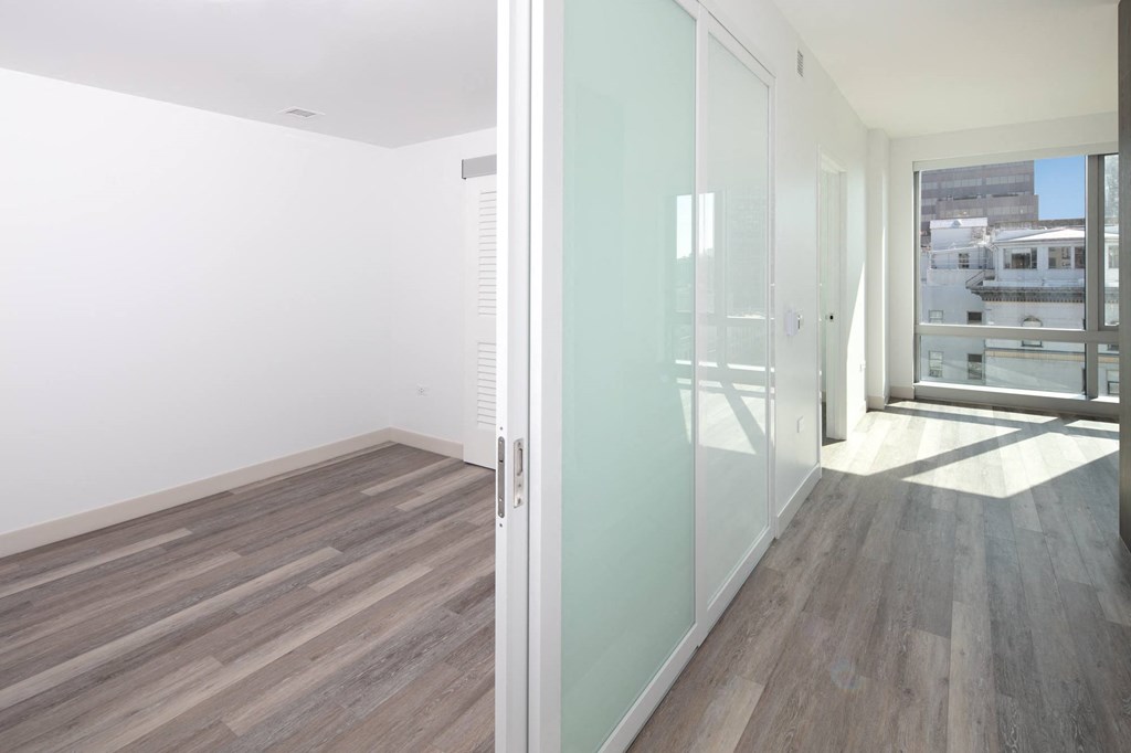 a bedroom with a medium sized window and a door that leads to a balcony