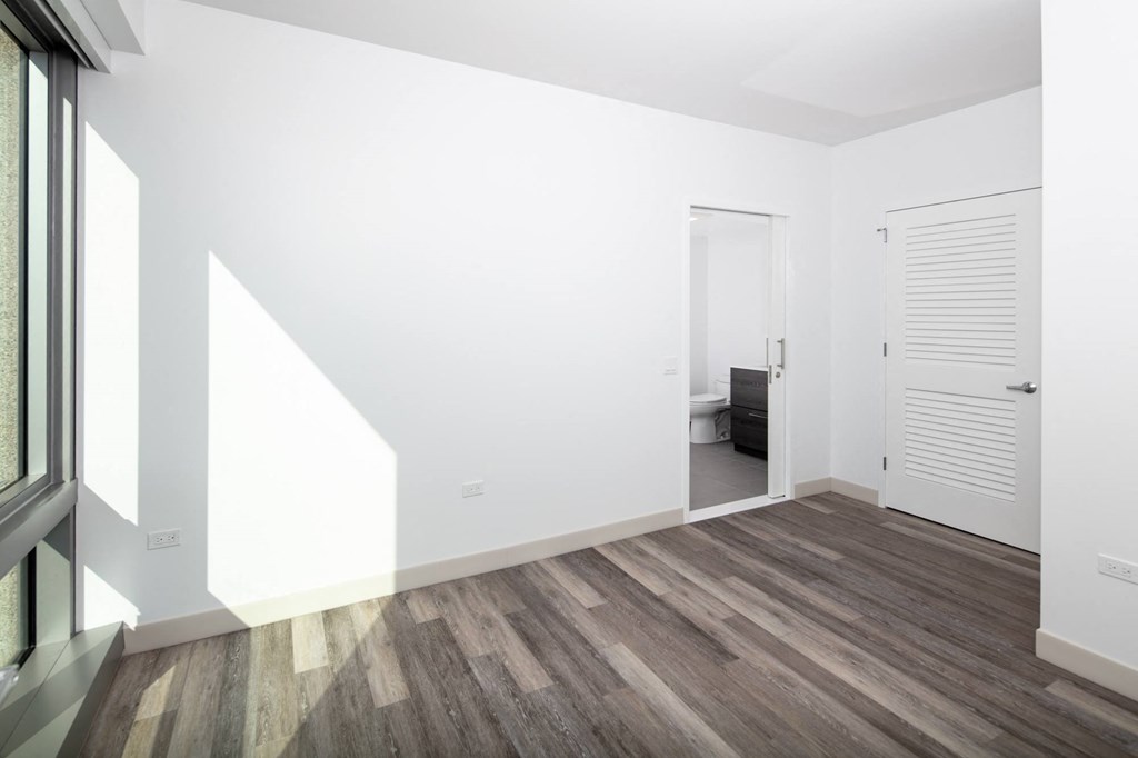 a bedroom with white walls and a wooden floor