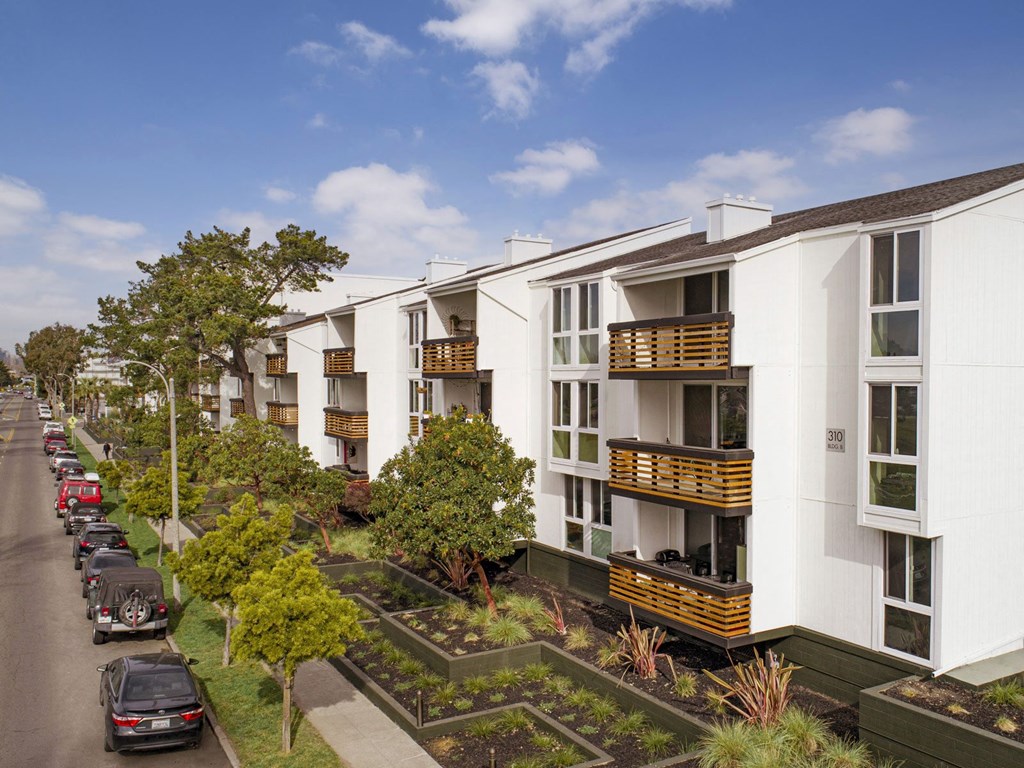 a row of white apartment buildings with balconies and a parking lot