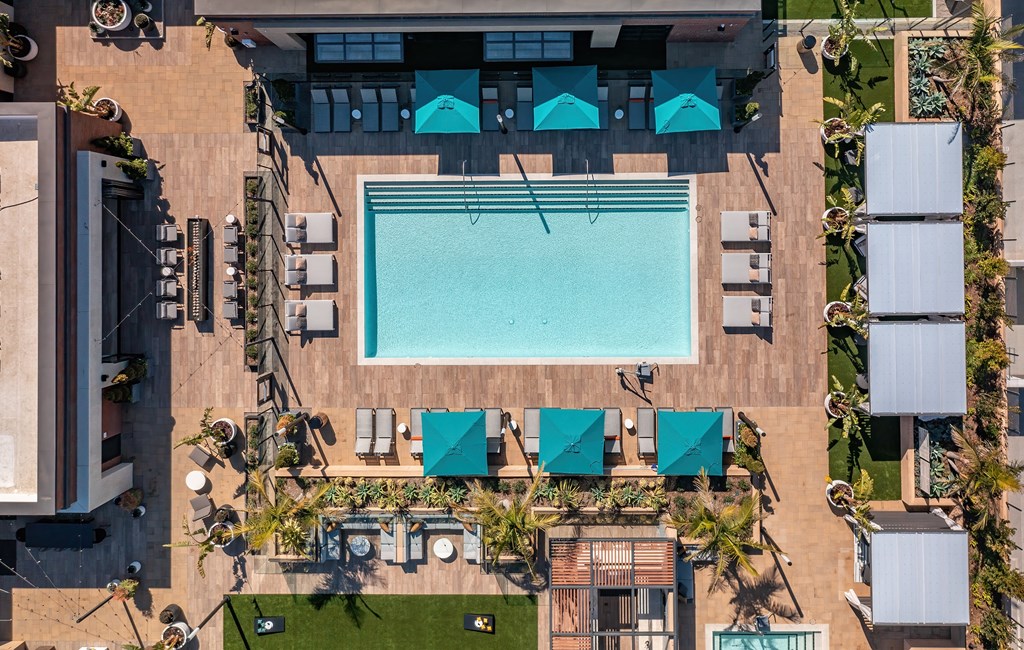 an overhead view of a resort style pool with lounge chairs and umbrellas