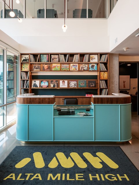 A reception area with a blue counter and a sign that says Alta Mile High.