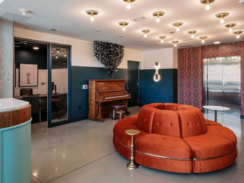 A living room with a piano and a red couch.