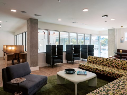 A living room with a black sofa, a white coffee table, and a green rug.