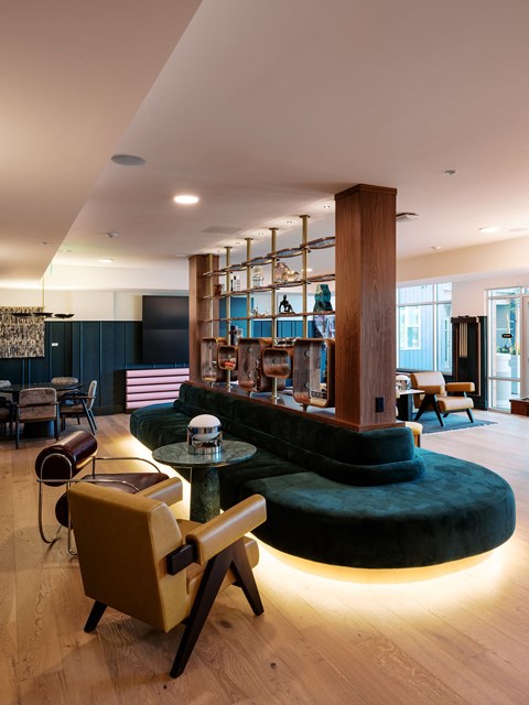 A modern living room with a green couch and a wooden bookshelf.