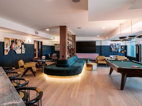 A room with a pool table and a bar area.