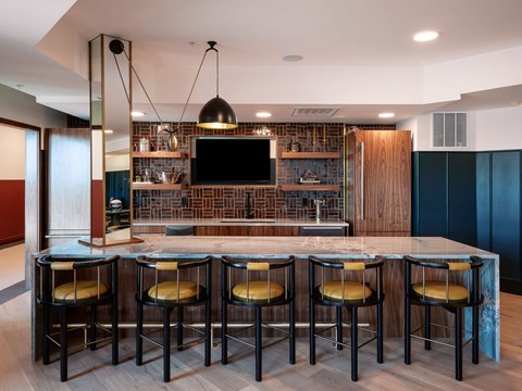 A modern bar with a brick backsplash and four stools.