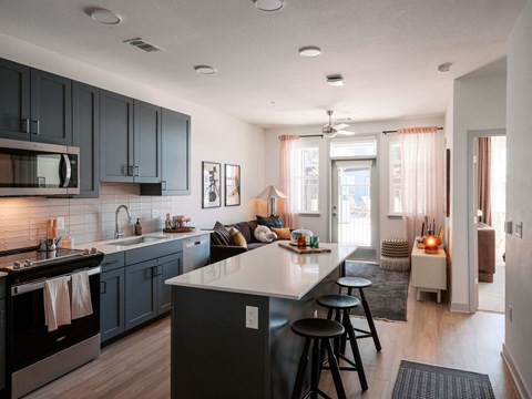 A modern kitchen with dark grey cabinets and a white countertop.
