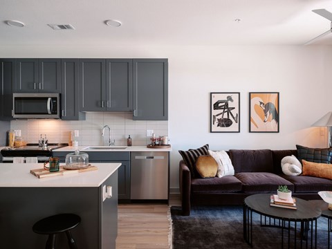 A modern kitchen with dark grey cabinets and a black stool.