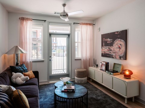 A living room with a couch, a coffee table, a side table, a lamp, a bookshelf, and a painting on the wall.
