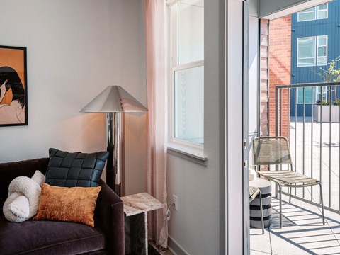A living room with a purple couch and a lamp.