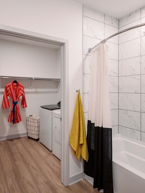 A red robe hangs on a white closet door next to a yellow towel.