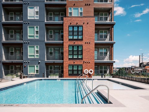 A large apartment building with a pool in front.