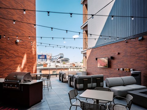 A rooftop patio with tables and chairs and string lights.