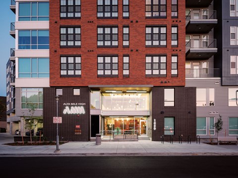 A tall building with a red brick facade and a sign that reads "17 Mile High Apartments.".