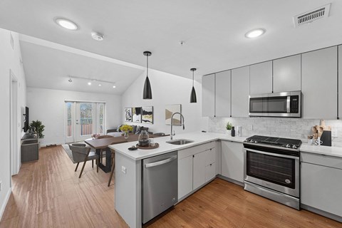 A modern kitchen with stainless steel appliances and wooden floors.