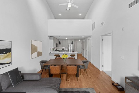 A modern living room with a grey couch and a wooden dining table.