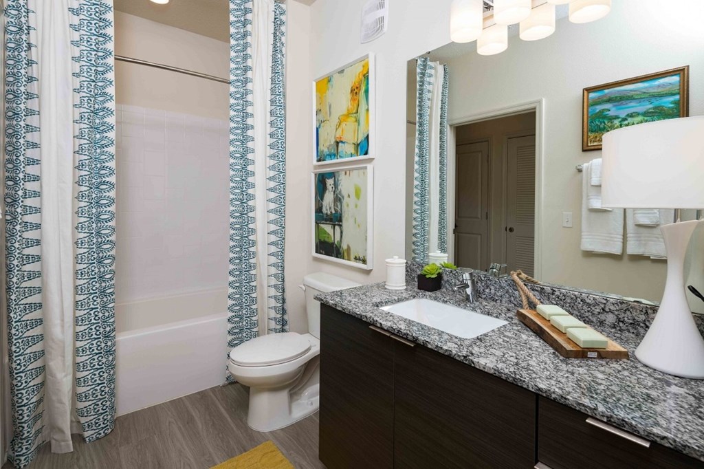 A bathroom with a toilet, sink, and shower curtain.