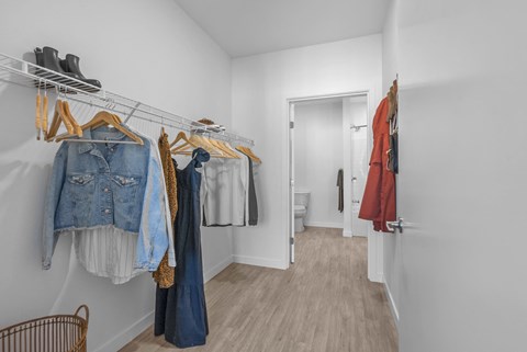 A hallway with clothes hanging on a rack and a door at the end.