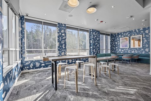 A room with a table and chairs in front of a window with a view of trees outside.