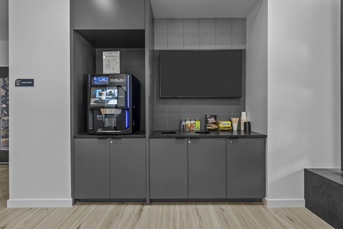 A vending machine with a variety of snacks and drinks is located in a corner of a room with a grey cabinet and a blackboard.