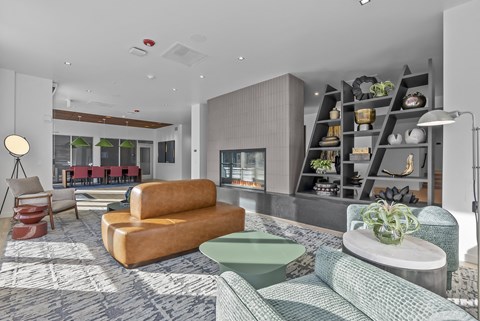 A modern living room with a large sofa, a coffee table, and a shelf with plants.
