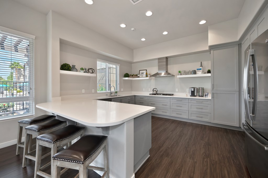 A kitchen with a white counter and brown stools.