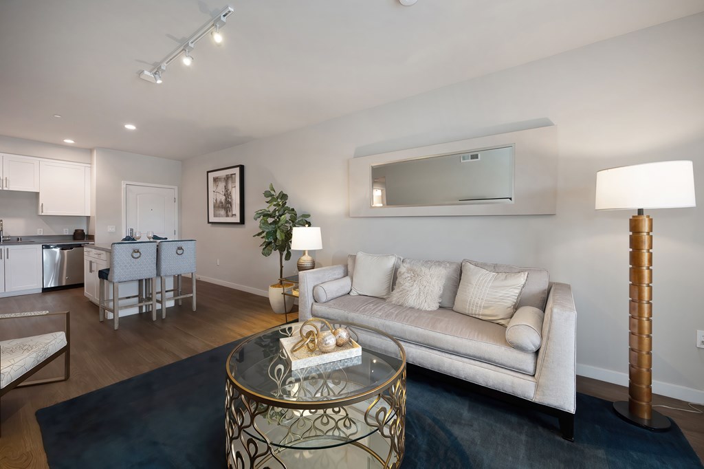A modern living room with a white couch and a glass coffee table.